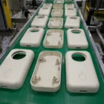 ABS consumer product housing parts after injection molding on conveyor belt