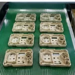 Injection molded plastic parts after demolding on production conveyor